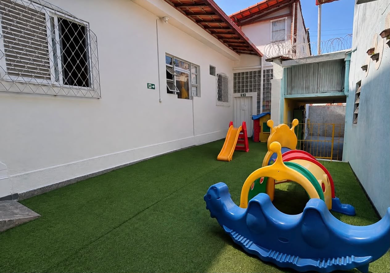 Parquinho com grama sintética e brinquedos para os pequenos