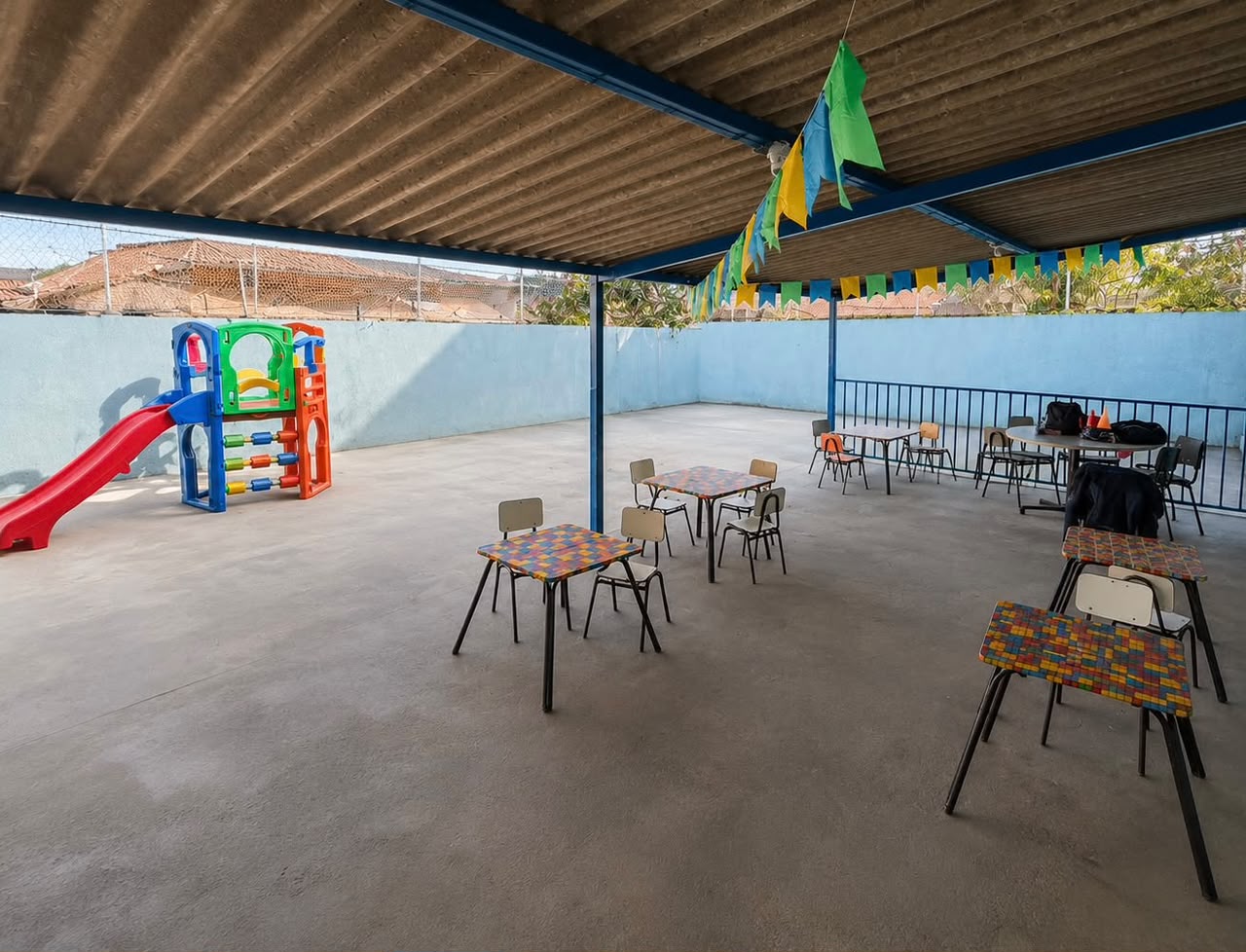 Pátio coberto com mesas coloridas e escorregador
